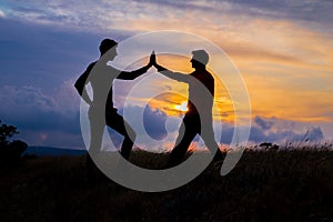 Teamwork couple hiking help each other trust assistance silhouette in mountains, sunset. Teamwork of two men hiker helping each
