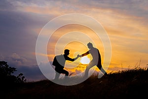 Teamwork couple hiking help each other trust assistance silhouette in mountains, sunset. Teamwork of two men hiker helping each