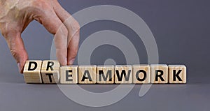 Teamwork and dream work symbol. Businessman turns wooden cubes and changes the word `dreamwork` to `teamwork`. Beautiful grey photo