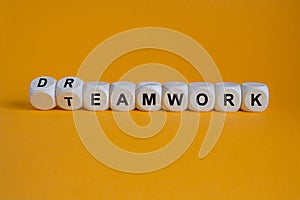 Teamwork and dream work symbol. Turned wooden cubes and changes the word teamwork to dreamwork. Beautiful orange background. photo
