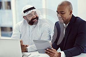 Teamwork, the foolproof way of getting things done. two businessmen using a digital tablet and laptop while having a