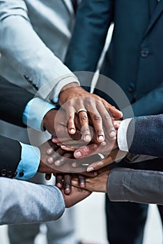 Teamwork gives us the strength to succeed. Closeup shot of a group of businesspeople joining their hands together in