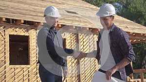 Teamwork handshake. Concept building constructing architect slow motion video. Two men builder in helmets shake hands