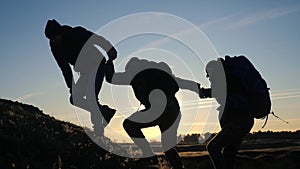 Teamwork help business three men hold hand travel silhouette concept. group of tourists lends a helping hand climb the