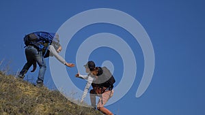 teamwork help business travel concept couple man and woman. of tourists lends a helping hand climb the cliffs mountains