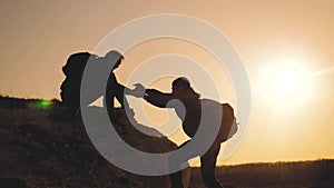 Teamwork help business travel silhouette concept. group of tourists lends a helping hand climb the cliffs mountains