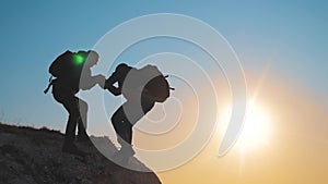 Teamwork help business travel silhouette concept. group of tourists lends a helping hand climb the cliffs mountains