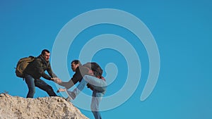 Teamwork help business travel silhouette lifestyle concept. Group of tourists lends a helping hand climb the cliffs