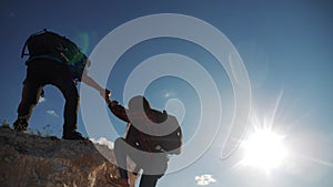 Teamwork help business travel silhouette slow motion video concept. Helping hand silhouette between two climbers