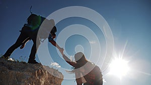 Teamwork help business travel silhouette slow motion video concept. Helping hand silhouette between two climbers