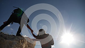 teamwork help business travel silhouette slow motion video concept. Helping hand silhouette between two climbers