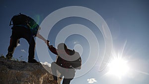 Teamwork help business travel silhouette slow motion video concept. Helping hand silhouette between two climbers