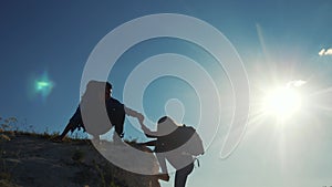 Teamwork help business travel silhouette slow motion video concept. Helping top hand silhouette between two climbers