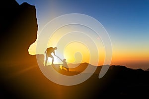 Teamwork helping hand couple climbing at sunset