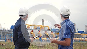 Teamwork. industry gas production station concept. slow motion video. two engineers in helmets are lifestyle studying