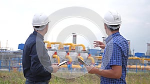 Teamwork. industry gas production station concept. slow motion video. two engineers in helmets are studying lifestyle
