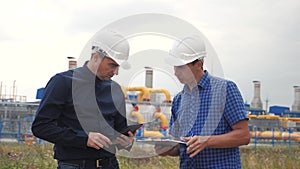 Teamwork. industry gas production station concept. slow motion video. two engineers in helmets are studying working with