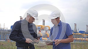 Teamwork. industry gas production station concept. slow motion video. two engineers in helmets are studying working with