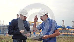 Teamwork. industry gas production station concept. Slow motion video. Two engineers in helmets are studying working with