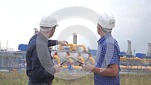 Teamwork. industry gas production station concept. slow motion video. two lifestyle engineers in helmets are studying