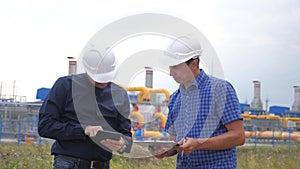 Teamwork. industry gas production station lifestyle concept. slow motion video. two engineers in helmets are studying