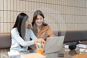 Teamwork and Learning. Two friends sharing laughter and knowledge while studying on a laptop.