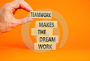 Teamwork makes dream work symbol. Concept words Teamwork makes the dream work on wooden blocks on beautiful orange background.
