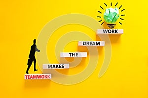 Teamwork makes dream work symbol. Concept words Teamwork makes the dream work on wooden blocks on beautiful yellow background.