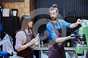 Teamwork, man and woman in aprons working together at bar counter in coffee shop cafe