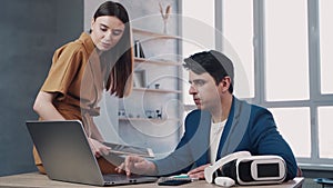 Teamwork in modern office, man and woman managers look at the laptop screen and talks