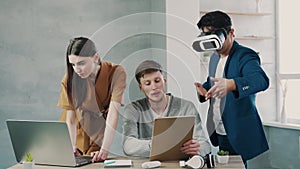 Teamwork in modern office, mans and woman managers look at the computer screen and using virtual reality headset