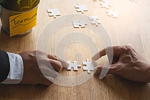 Teamwork, partners, connection concept. Hands of two businessmen merging jigsaw puzzle on the working table