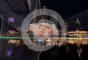 Teamwork, partnership and success concept. Double exposure of business handshake for successful of investment deal and city night