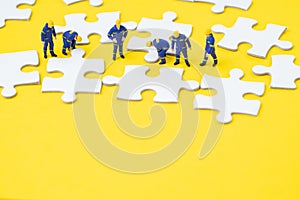 Teamwork, problem solution or business success strategy concept, miniature people employee or staffs help complete white jigsaw p