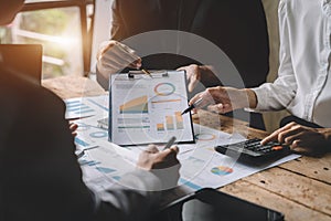 Teamwork process, Business team using a calculator to calculate the numbers of statistic business profits growth rate on documents