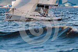 Teamwork in sailing regatta at sunset, sailing yacht in roll, big waves, hot racing