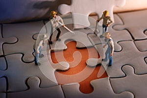 Teamwork and Solving Problem Concept. Group of Miniature Worker Men Found Something Wrong on the Work Process a Piece of Jigsaw