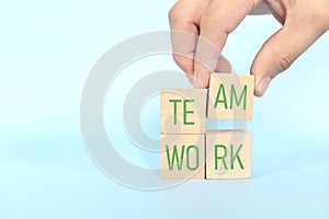 Teamwork and team building business concept. Hand putting together wooden blocks wood puzzle pieces in blue background.