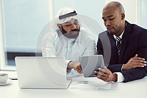 Teamwork and tech, the best tools for productivity. two businessmen using a digital tablet and laptop while having a