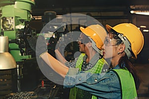 Teamwork two female Check the readiness of the drill machine of the engine parts industry.