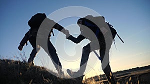 Teamwork two men help helping hand business travel silhouette concept. two tourists lends a helping hand climb the