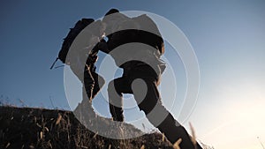 Teamwork two men help helping hand business travel silhouette concept. two tourists lends a helping hand climb the