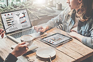 Teamwork, two young business woman sitting at table,drinking coffee and working online.