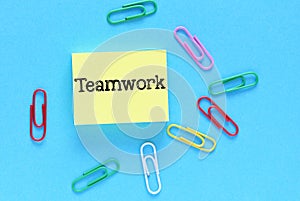 TEAMWORK word on yellow piece of paper and blue background