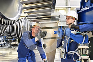 Teamwork - workers manufacturing steam turbines in an industrial