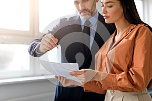 Teamwork at workplace. Businessman and businesswoman reading finance report and talking, looking at document, cropped