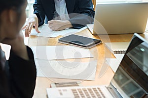 Teamwork.young businesswomen sitting at table write down on paper and other one your laptop and smartphone discuss business