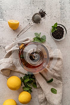 Teapot with black tea decorated with mint leaves, lemons and dry tea leaves top view flat lay