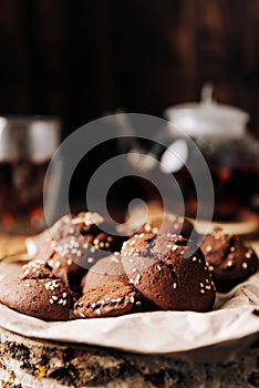 Teapot with black tea and homemade chocolate cookies on a brown natural wooden background