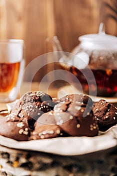 Teapot with black tea and homemade chocolate cookies on a brown natural wooden background